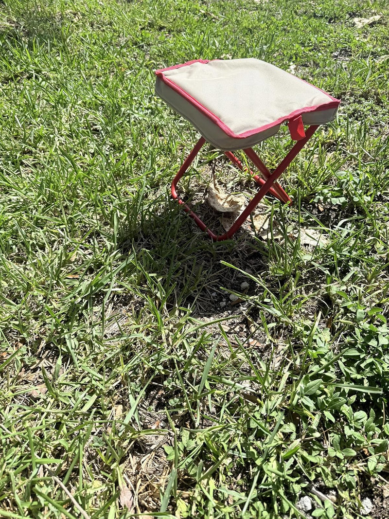 Small red stool with a white cushion on a grassy area